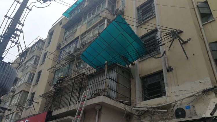 蓝色雨棚摇摇欲坠当时,塑料雨棚两只角搭在2楼居民家的晾衣杆和